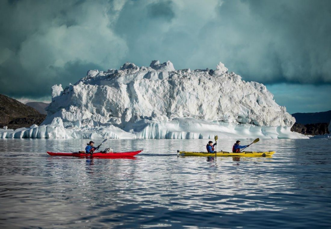 Greenland_visit_greenland_Mads_Phil_kayaking_past_iceberg-1100x760