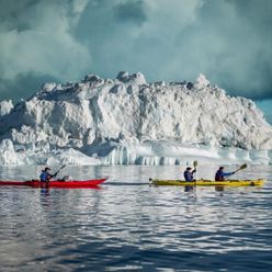 Greenland_visit_greenland_Mads_Phil_kayaking_past_iceberg-1100x760